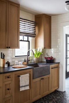 a kitchen with wooden cabinets and black counter tops, white tiles on the walls and floor