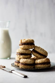 a stack of cookies sitting on top of a plate next to a glass of milk