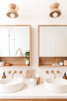 two bathroom sinks with mirrors above them in front of a wall mounted mirror and light fixture