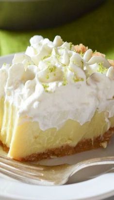 a piece of pie on a white plate with a fork and green cloth in the background