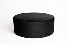 a black round ottoman sitting on top of a white floor