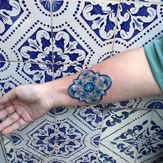 a person's arm with a blue flower tattoo on the left side of their arm