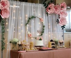 a table topped with cakes and desserts next to a wall covered in pink flowers