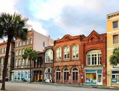 an old brick building with palm trees in the foreground and other buildings on either side