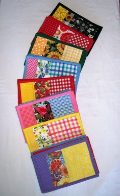 four quilted placemats are lined up on a tablecloth with different patterns and colors