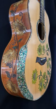 an acoustic guitar with sunflowers painted on it