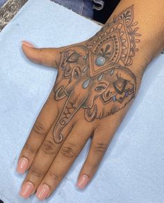 an elephant tattoo on the palm of a woman's hand, which is decorated with jewels