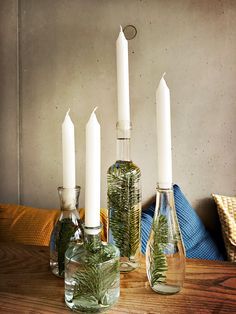 three glass bottles with candles in them sitting on a table