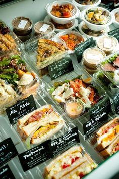 many different types of food are on display in plastic containers and trays for sale