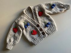 a knitted sweater with cherries and buttons on it