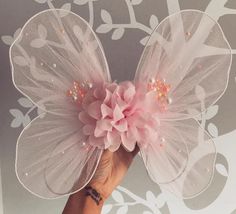 a hand holding a pink flower on top of a white table cloth covered in sequins