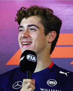 a young man holding a microphone in front of a purple and orange background with the words williams written on it