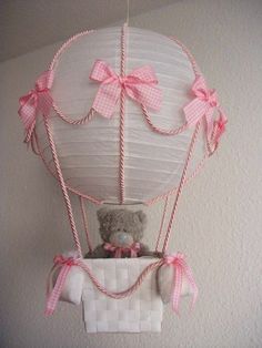 a teddy bear in a hot air balloon with pink bows on it's head