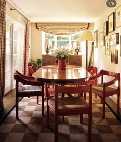 a dining room table with chairs and pictures on the wall in front of it's windows