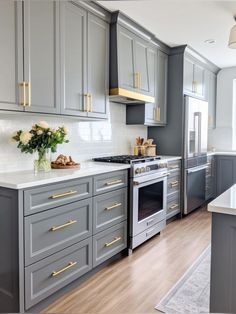 a kitchen with gray cabinets and gold pulls on the handles, white marble counter tops