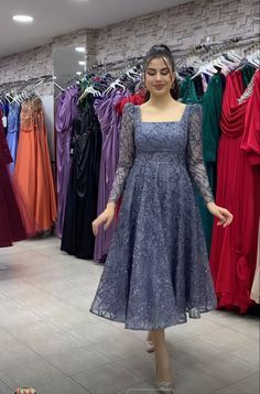 a woman standing in front of a rack of dresses at a clothing store with her hands on her hips