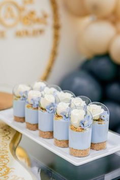 small desserts are arranged on a white platter with blueberries in the background