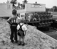 two young boys standing next to each other in front of a boat