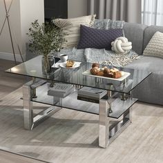 a glass coffee table sitting on top of a wooden floor next to a gray couch