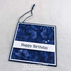 a birthday card with blue flowers and the words happy birthday hanging from it's side