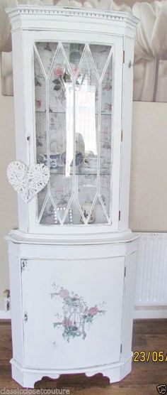 a white china cabinet sitting on top of a hard wood floor next to a wall