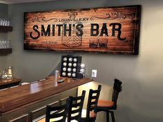 there is a wooden sign that says smith's bar on the wall next to some chairs