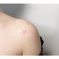 a small heart tattoo on the back of a woman's left shoulder and arm