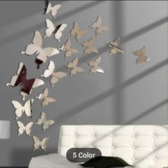 a white couch sitting next to a wall with butterflies flying from it's back