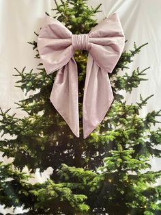 a pink bow on top of a christmas tree