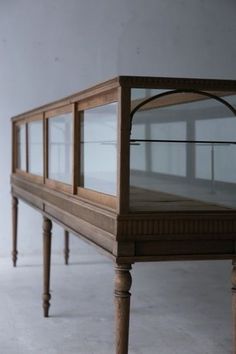 an old wooden table with glass doors on it's top and bottom shelf in the middle