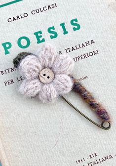 a crocheted flower brooch sitting on top of a book