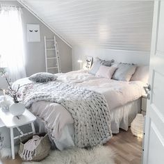 a bedroom with white walls and flooring has a large bed covered in fluffy blankets