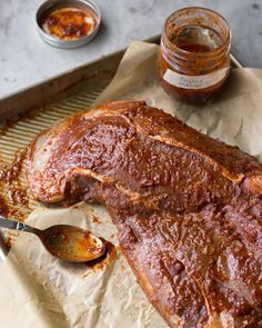 a large piece of meat sitting on top of a pan next to some sauces