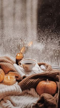 some candles are sitting on a window sill next to pumpkins and other items