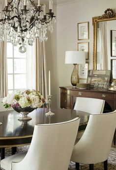 an elegant dining room with chandelier and white chairs in front of the table