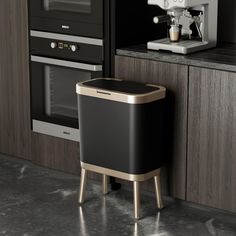 a black and gold trash can sitting next to a coffee maker on a counter top