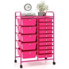 a pink cart with lots of drawers and a clock on the top of it next to a plant