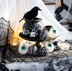 a black bird sitting on top of an ornate vase filled with decorated eggs and candles