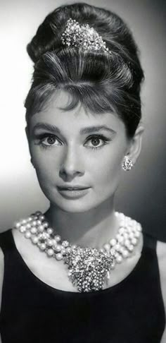 a black and white photo of a woman wearing pearls