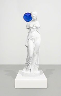 a white statue holding a blue frisbee on top of it's head