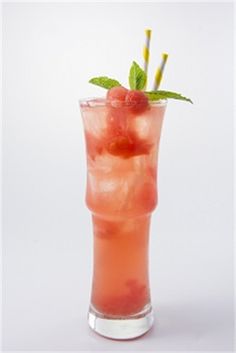 a tall glass filled with watermelon and mint garnished with two straws