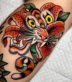 a tiger tattoo on the leg of a man with oranges and green leaves around it