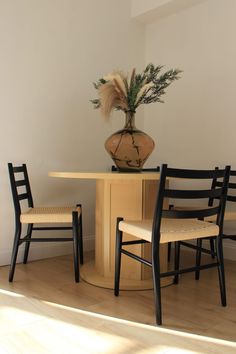 a table with two chairs and a vase on top of it in the middle of a room