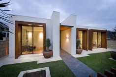 a modern house with large potted plants in the front yard