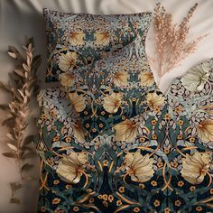 an image of a bed set with flowers and leaves on the comforter cover, next to a plant