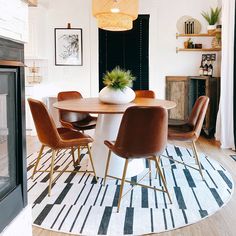 a dining room table with chairs and a rug on the floor in front of it