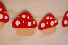 red and white paper mushrooms are hanging on a string