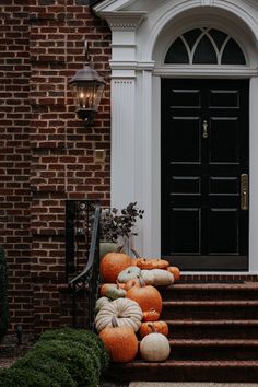 pumpkins and gourds are stacked up on the steps in front of a house