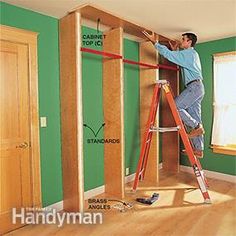 a man standing on a ladder working on a wall in a room with green walls