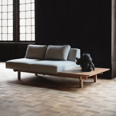 a white couch sitting on top of a wooden table in front of a window next to a teddy bear